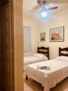Pousada Castanheira في غواراباري: غرفة نوم بسريرين ومروحة سقف