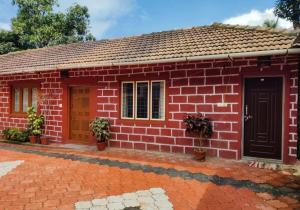 a small red brick house with a black door at cocostay coorg in Madikeri