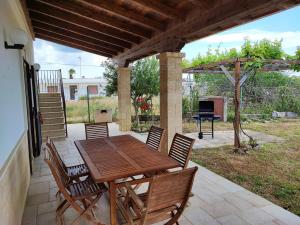 een houten tafel en stoelen op een patio bij Villa Torre San Giovanni Lido Sabbioso 151-Verso Sud in Torre San Giovanni Ugento