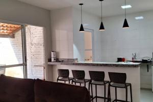 a living room with a bar with four stools at Casa Temporada Terra Nova in Uberaba +7 photos