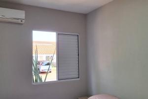 a window in a white room with a car outside at Casa Temporada Terra Nova in Uberaba