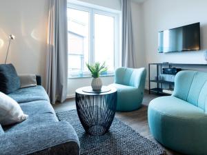 ein Wohnzimmer mit einem Sofa, 2 Stühlen und einem Tisch in der Unterkunft Hafenspitze App 22 in Wismar