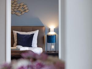 a bedroom with a bed with a blue pillow and a lamp at Hafenspitze App 37 in Wismar