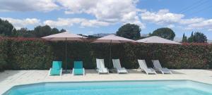 eine Gruppe von Stühlen und Sonnenschirmen neben einem Pool in der Unterkunft L'Ansolanette - Chambre d'hôtes in Fuveau