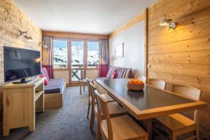 a living room with a dining room table and a kitchen at Résidence Pierre & Vacances Les Néréides in Belle Plagne