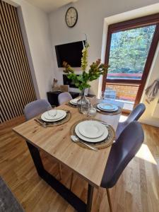 a wooden table with plates and a vase on it at Apartament Pod Brzyzkiem & Spa in Zakopane