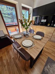 a dining room table with a vase of flowers on it at Apartament Pod Brzyzkiem & Spa in Zakopane