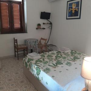 ein Schlafzimmer mit einem Bett, einem Tisch und einem Stuhl in der Unterkunft Casa Vacanze "Villa Angelina" in Lipari