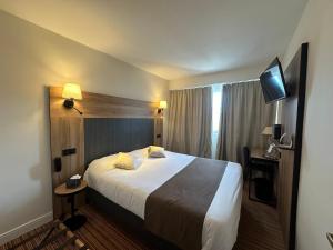 ラ・ロッシュ・シュル・ヨンにあるThe Originals City, Hôtel Napoléon, La Roche-sur-Yon (Inter-Hotel)のベッドとテレビが備わるホテルルームです。