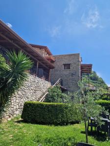 a house with a stone wall and a palm tree at Agriturismo Orrido di Pino in Agerola