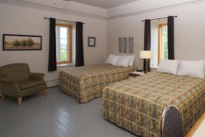una habitación de hotel con 2 camas y una silla en Auberge du Couvent, en Saint-Casimir