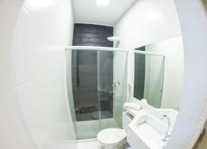 a white bathroom with a toilet and a sink at Hotel Veneza in Itabuna