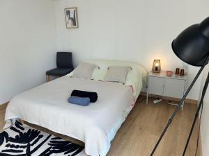 a bedroom with a white bed with a black lamp at La Chambre de Kerly in Pléguien