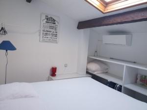 a white bedroom with a bed and a lamp at Appartement climatisé à 800m de la plage in Fréjus