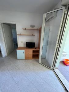 um quarto com uma televisão e uma porta de vidro deslizante em Residence Verde Pineta em Principina a Mare