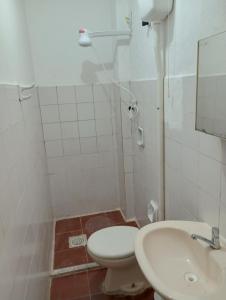 a white bathroom with a toilet and a sink at Angelus Hotel & Estacionamento in Campos dos Goytacazes