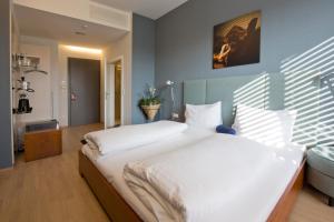 una camera da letto con un letto grande con lenzuola bianche di Hotel Lava Inn - 24 h Check-In - Nähe LKH, Landeskrankenhaus, Feldbach a Feldbach