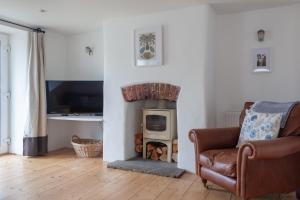 sala de estar con chimenea, silla y TV en Cosy Beachside Cottage en Bigbury