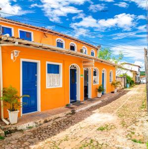 an orange building with blue doors on a street at Pousada Nativos Lençois in Lençóis