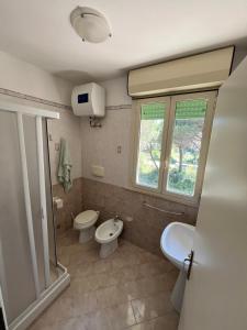 a bathroom with two toilets and a sink and a window at Residence Verde Pineta in Principina a Mare +23 photos