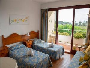 a hotel room with two beds and a balcony at Estudio with sea view Cala Martina in Cala Llenya