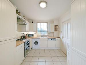 cocina blanca con electrodomésticos blancos y ventana en 4 The Clockhouse , Midhurst, en Midhurst