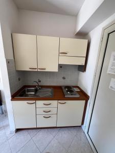 a small kitchen with white cabinets and a sink at Residence Verde Pineta in Principina a Mare