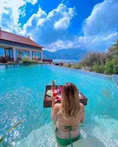 a woman sitting at a table in the water near a pool at Villa Danu in Kintamani