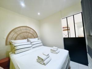 una camera da letto con un letto bianco e asciugamani di Appartement Frida de la Marina a Les Trois-Îlets