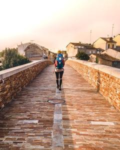 a woman walking down a brick bridge with a backpack at Hotel Burlada in Burlada