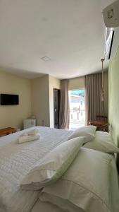 Humaita Pousada في إيتاكاري: غرفة نوم بسرير كبير ومخدات ونافذة