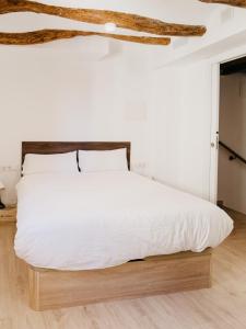 MasroigにあるCamins del Priorat : Ermita sant Gregori bisの白いベッド1台(木製ヘッドボード付)が備わるベッドルーム1室が備わります。