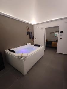 a large white tub in a room with a bedroom at Le Suite di Magda Relax & Rooms in Polignano a Mare