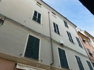 a white building with green shutters on it at Casa Misette 200mq a due passi dal mare in Alassio