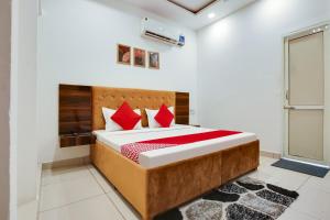 um quarto com uma cama grande e almofadas vermelhas em Flagship Hotel Cozy Comfort em Ludhiana