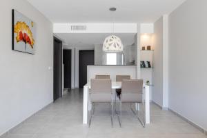 - une cuisine blanche avec une table à manger et des chaises dans l'établissement Nova SuperBeach 38, à Gran Alacant