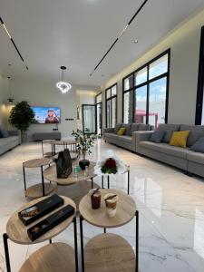 una sala de estar con sofás, mesas y ventanas en شاليه ضي, en Hail