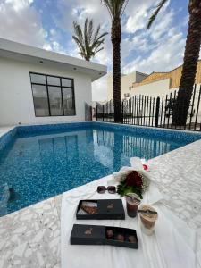 einen Tisch mit einem Tablett mit Speisen neben dem Pool in der Unterkunft شاليه ضي in Ha'il