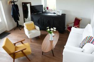 a living room with a white couch and chairs and a table at Maison bretonne rénovée proche bourg et plages in Plouguerneau