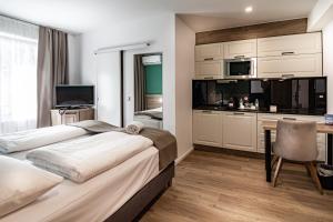 a bedroom with two beds and a desk and a kitchen at Sleep Inn Düsseldorf in Düsseldorf