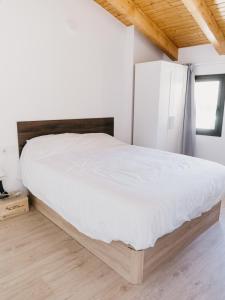 1 dormitorio con cama blanca y cabecero de madera en Camins del Priorat : Ermita Pinyeres en Masroig