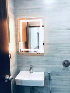 a bathroom with a white sink and a mirror at Sameena Guest House in Panchgani