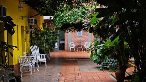 un patio con sillas blancas, mesas y plantas en Iguazu Hojas Verdes en Puerto Iguazú