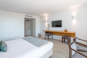 Schlafzimmer mit einem Bett und einem Schreibtisch mit einem TV in der Unterkunft Vale do Gaio Hotel in Torrão