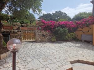 une terrasse en pierre avec une clôture et des fleurs roses dans l'établissement Villa Chiara Villetta con giardino IUN 4807, à Porto Pollo