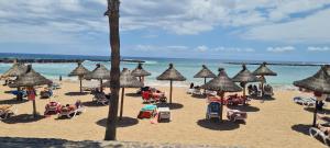 una spiaggia con molti ombrelloni e persone sulla sabbia di CASA PARAISO ad Arona