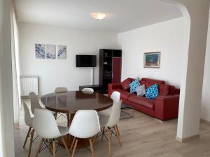 a living room with a table and a red couch at Casa Eva in Bibione