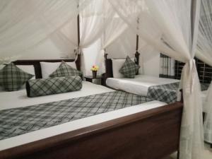 2 camas en una habitación con paredes blancas en Sigiriya Rock Gate Resort, en Sigiriya
