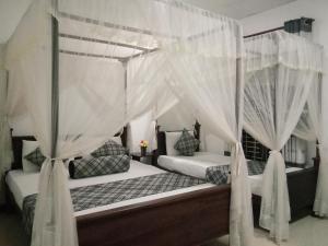 2 camas en un dormitorio con cortinas blancas en Sigiriya Rock Gate Resort, en Sigiriya