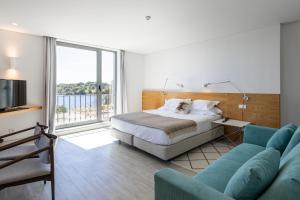 1 dormitorio con cama, sofá y TV en Vale do Gaio Hotel, en Torrão